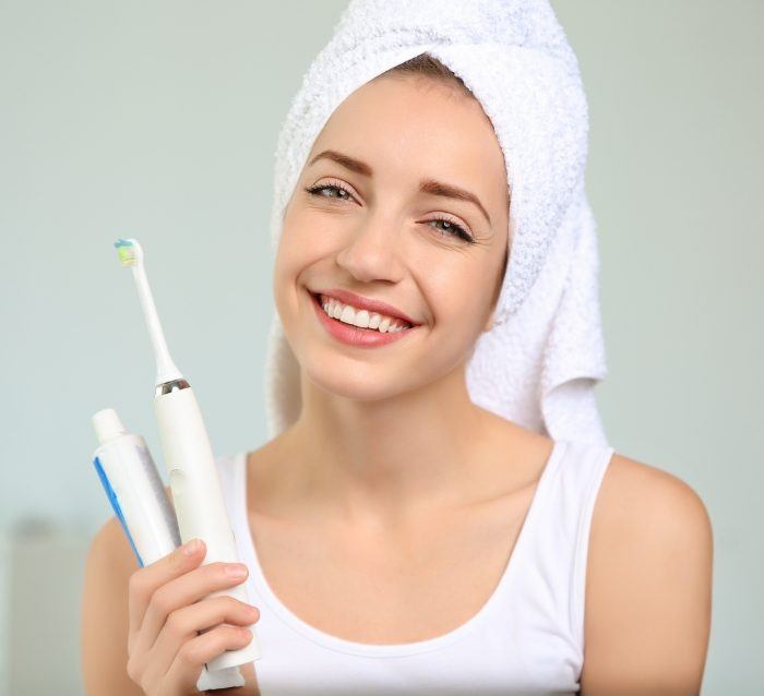 Smiling woman holding toothbrush after preventive dentistry visit