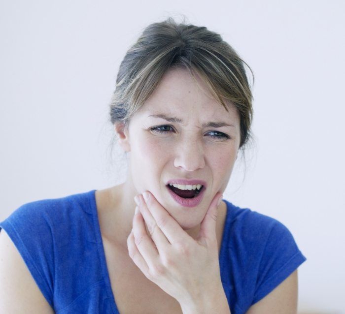 Woman holding jaw in pain before T M J treatment