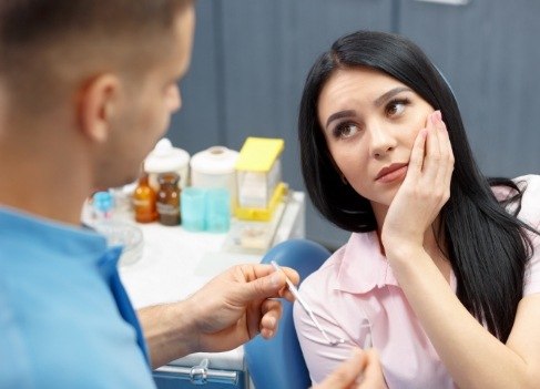 Woman holding cheek in pain before wisdom tooth extraction